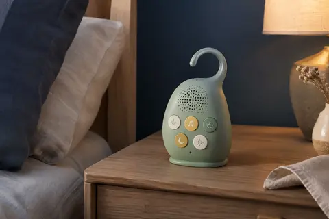 Machine à sons portable MyBaby verte posée sur une table de chevet dans une chambre calme